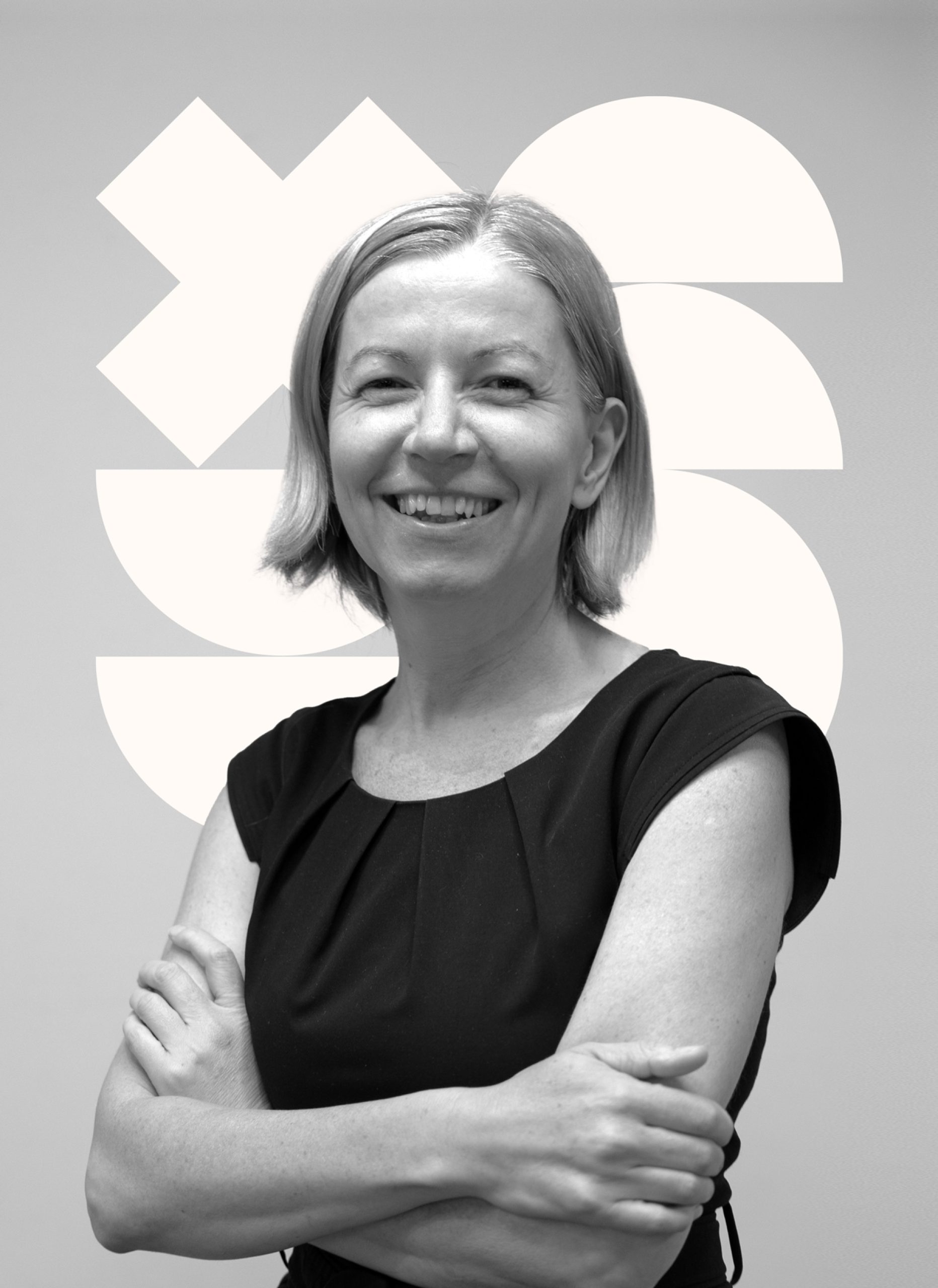 Smiling woman in black, arms crossed, company logo