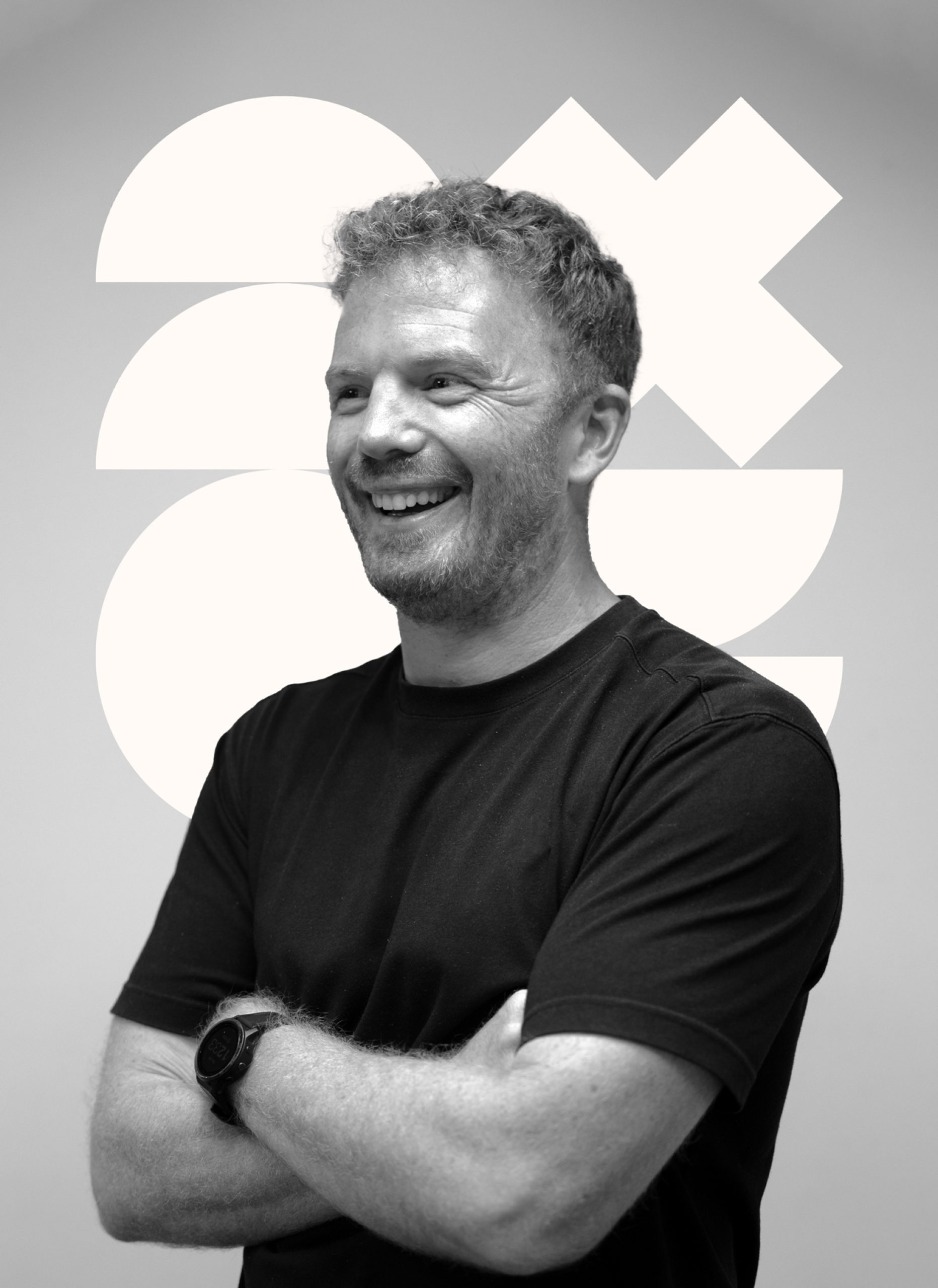 Man in black shirt smiling with arms crossed