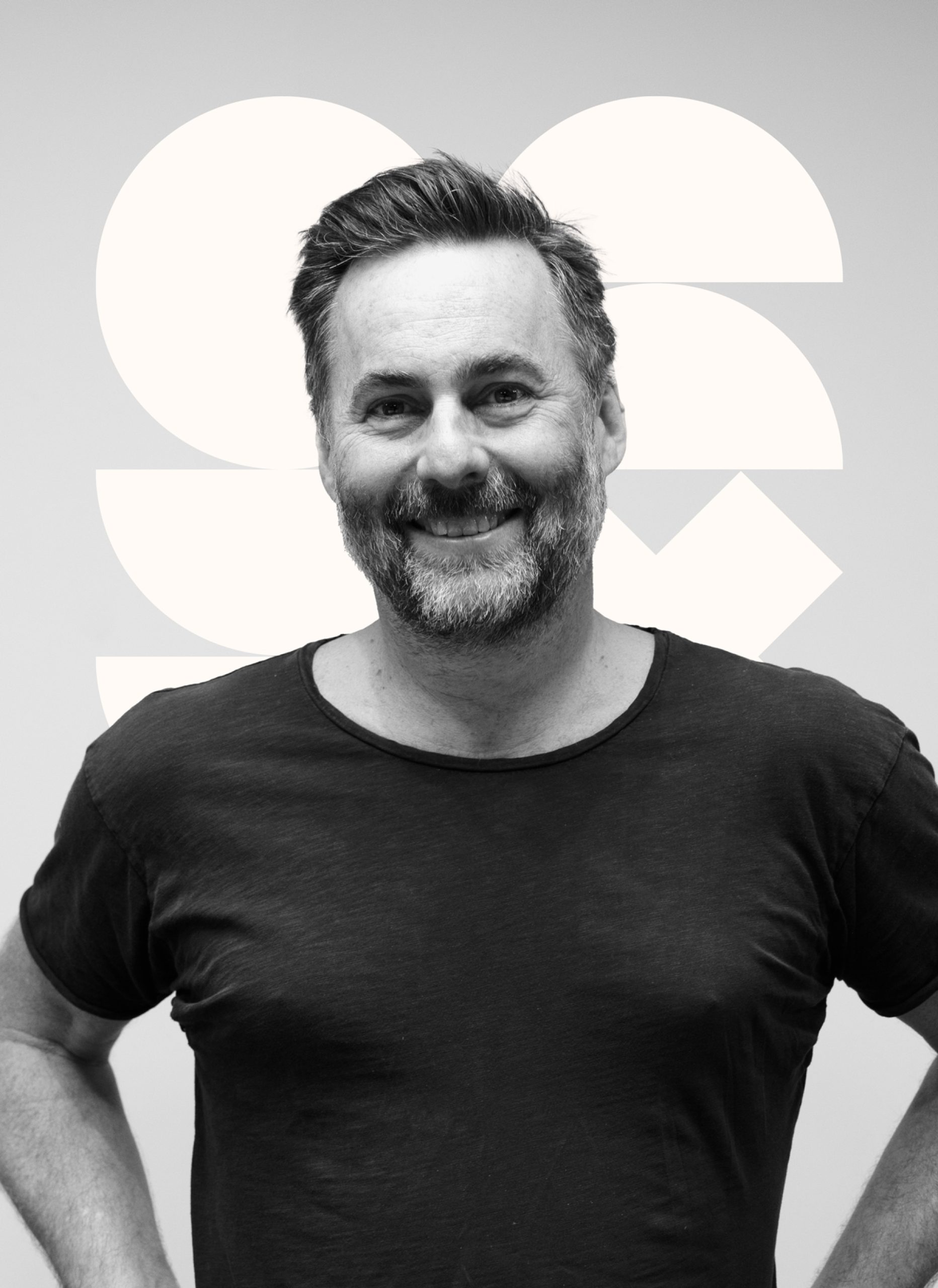 Smiling man with beard in black t-shirt against a white background